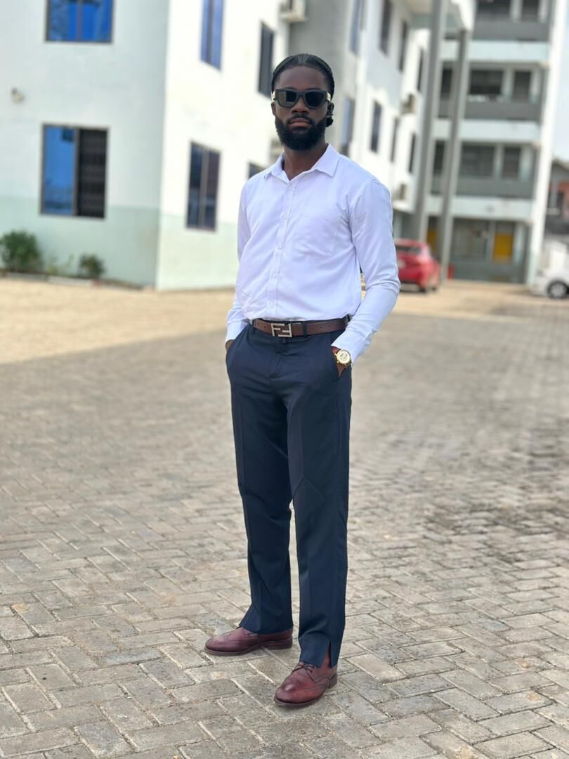 Joseph Panyin standing outdoors in a white shirt, navy trousers and sunglasses.